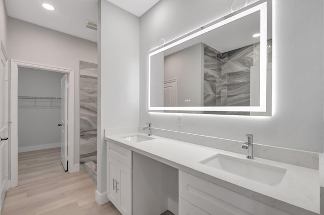 bathroom with tiled shower, vanity, and hardwood / wood-style floors