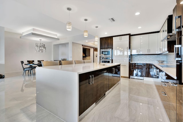 kitchen featuring decorative light fixtures, sink, dark brown cabinetry, and a spacious island