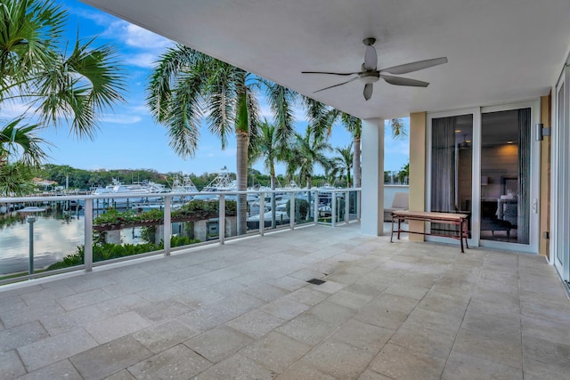 view of patio with a balcony, ceiling fan, and a water view