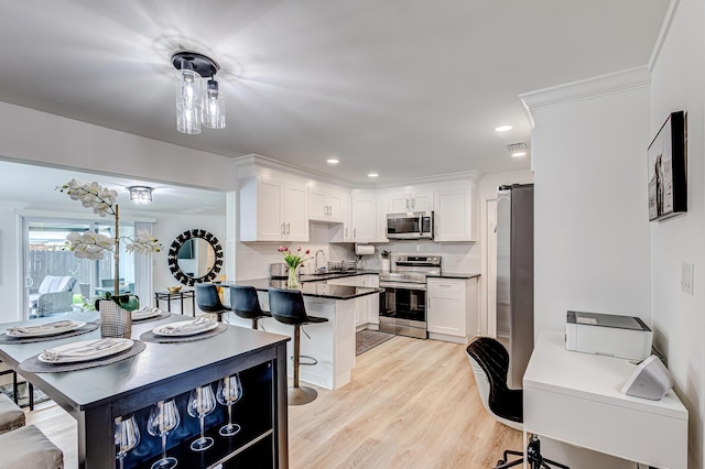 kitchen with light wood-type flooring, stainless steel appliances, backsplash, and white cabinets