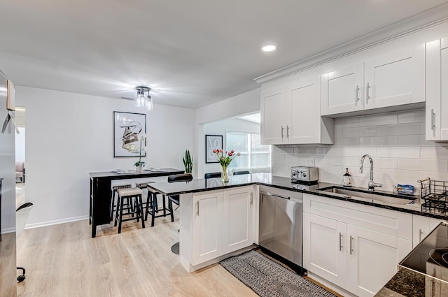 kitchen with dishwasher, kitchen peninsula, sink, light hardwood / wood-style flooring, and white cabinets