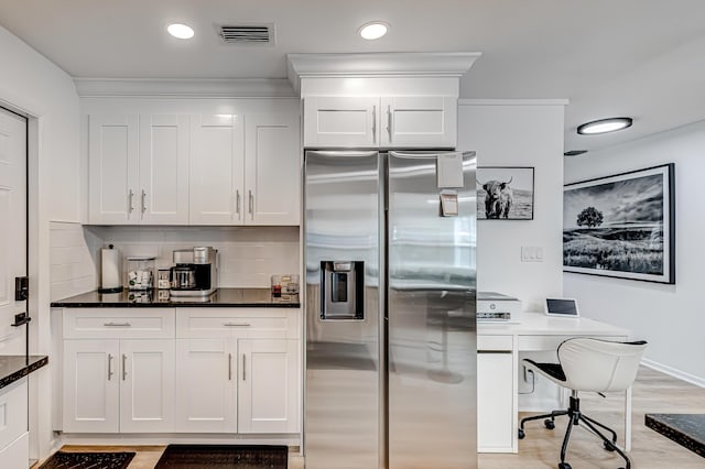 kitchen with white cabinetry, dark stone counters, decorative backsplash, stainless steel fridge with ice dispenser, and light wood-type flooring