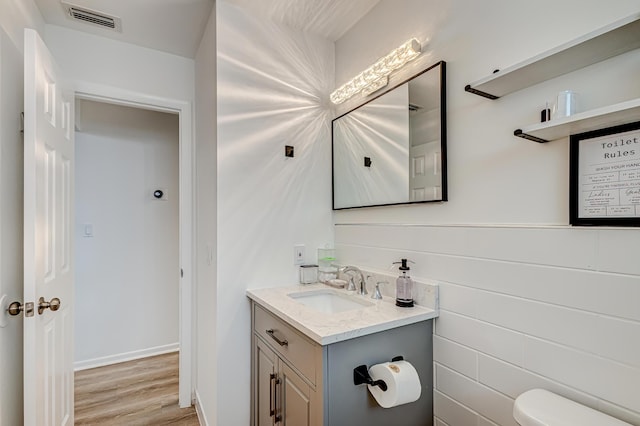 bathroom with toilet, wood-type flooring, and vanity