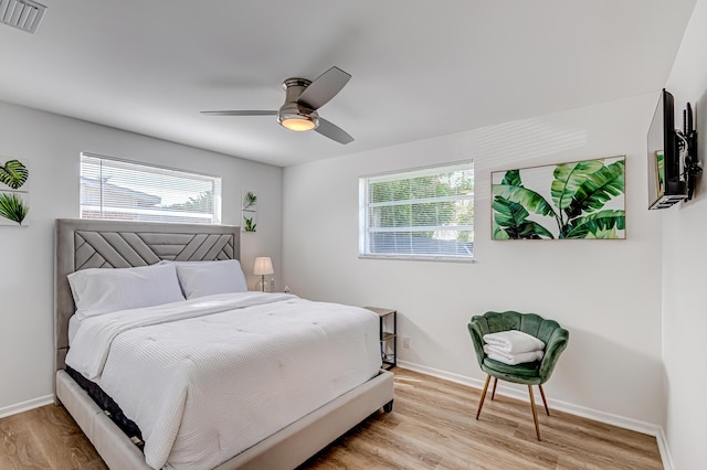 bedroom with ceiling fan, multiple windows, and light wood-type flooring