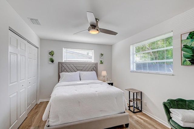 bedroom with ceiling fan, multiple windows, a closet, and light hardwood / wood-style flooring