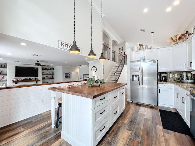 kitchen featuring stainless steel fridge with ice dispenser, ceiling fan, decorative light fixtures, white cabinets, and a breakfast bar