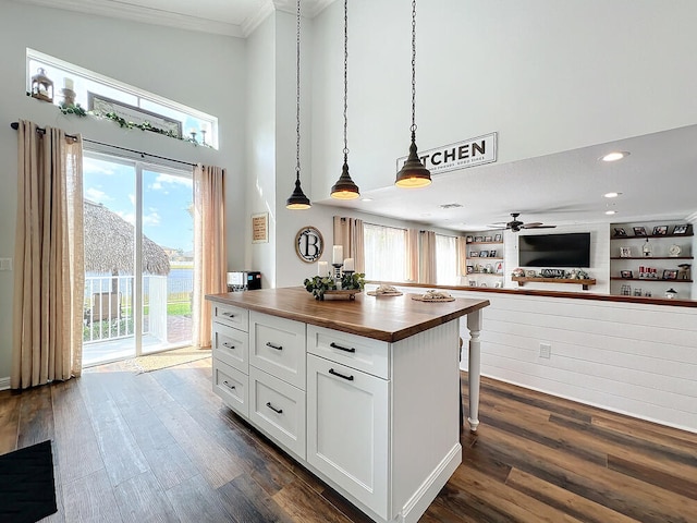 kitchen with a center island, wooden counters, decorative light fixtures, white cabinetry, and built in shelves