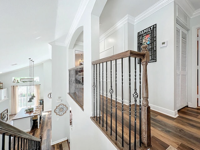 corridor with lofted ceiling, dark hardwood / wood-style flooring, ornamental molding, and a chandelier