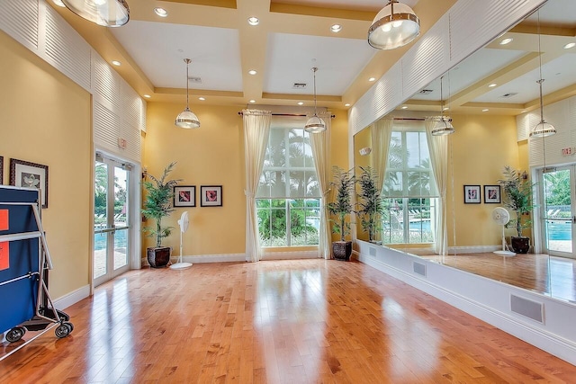 exercise area with light hardwood / wood-style floors, a towering ceiling, and french doors