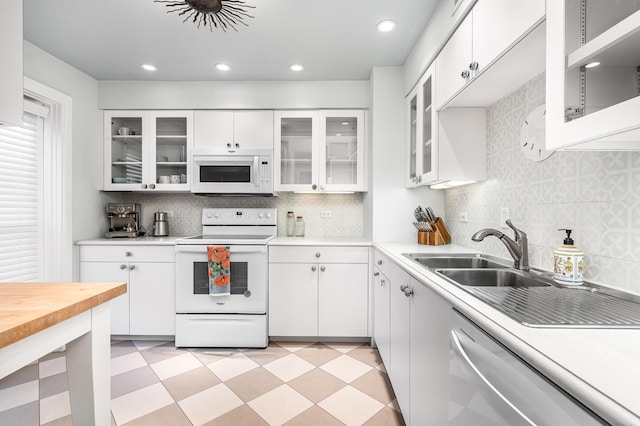 kitchen featuring white cabinetry, backsplash, white appliances, and sink