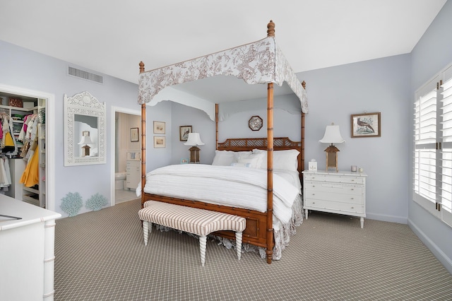 carpeted bedroom featuring a closet, a spacious closet, and ensuite bath