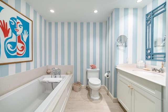 bathroom featuring toilet, a tub to relax in, and vanity