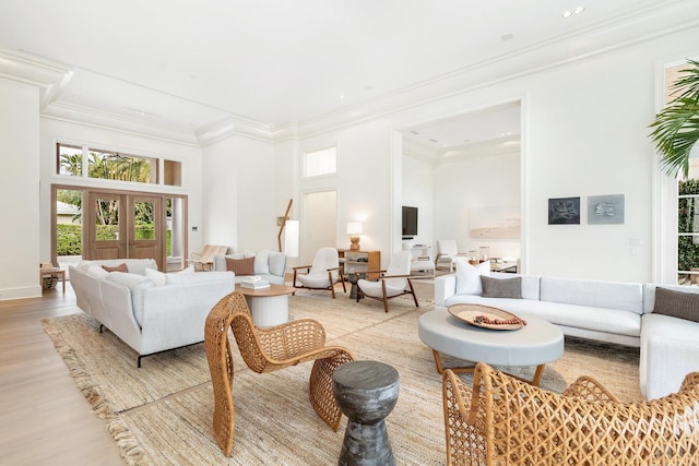 living room featuring light hardwood / wood-style flooring, crown molding, and a towering ceiling