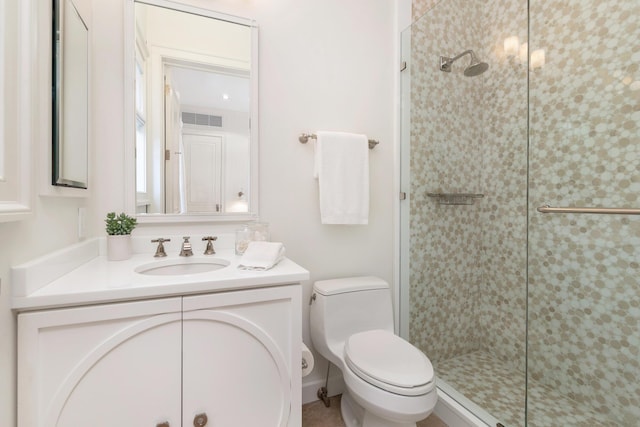 bathroom featuring toilet, a shower with door, and vanity