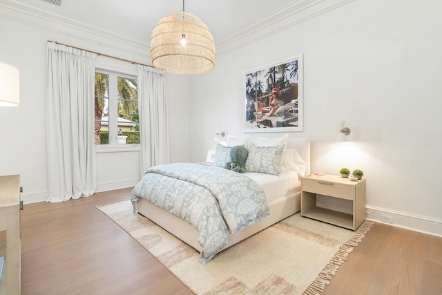 bedroom with ornamental molding and wood-type flooring