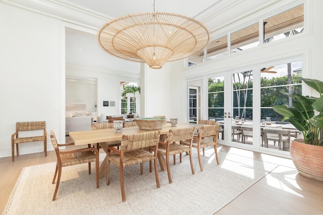 dining area with french doors, a towering ceiling, a chandelier, and hardwood / wood-style floors