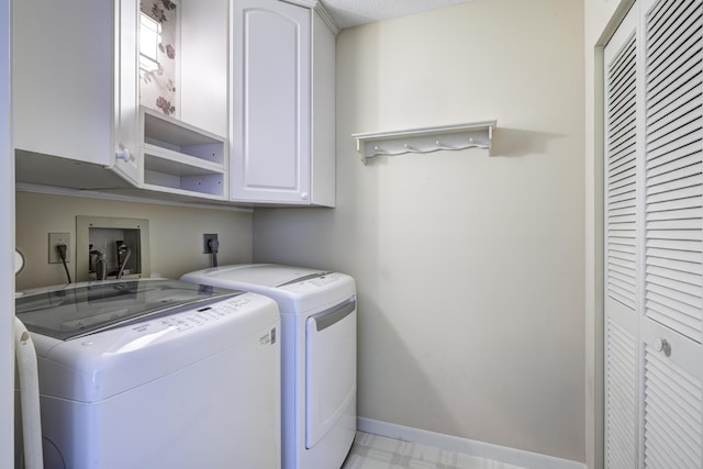 clothes washing area featuring cabinets and independent washer and dryer