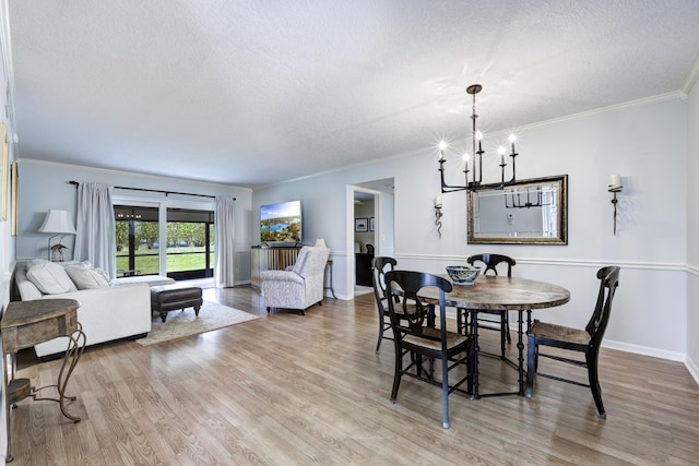 dining area featuring hardwood / wood-style floors, ornamental molding, a notable chandelier, and a textured ceiling