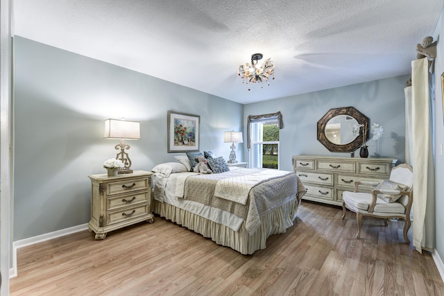 bedroom with an inviting chandelier, a textured ceiling, and light hardwood / wood-style flooring