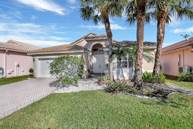 mediterranean / spanish-style home featuring a garage, a front lawn, and ac unit