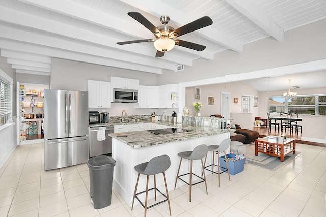 kitchen with a breakfast bar area, appliances with stainless steel finishes, white cabinets, a sink, and a peninsula