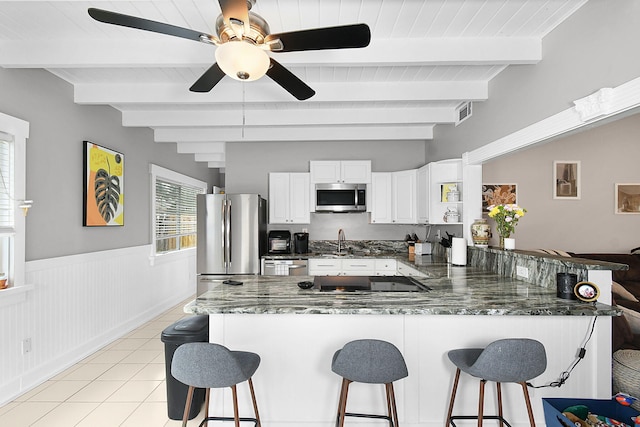 kitchen with appliances with stainless steel finishes, a breakfast bar, white cabinetry, sink, and kitchen peninsula