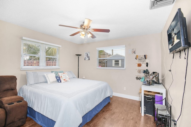 bedroom with baseboards, visible vents, ceiling fan, and wood finished floors