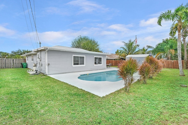 rear view of property with a yard, a pool with hot tub, and a patio area