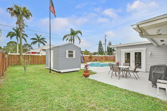 view of yard featuring a fenced in pool, a patio area, french doors, and a storage shed