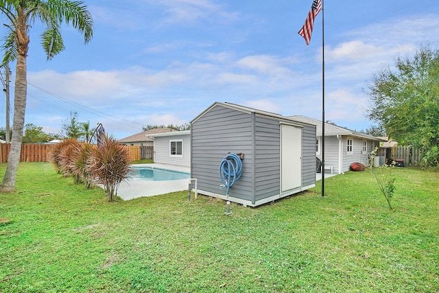 exterior space with a fenced in pool, a lawn, and a storage unit