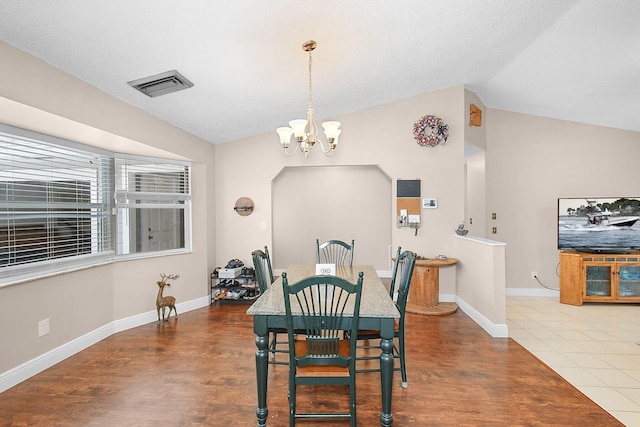 dining space with visible vents, an inviting chandelier, baseboards, vaulted ceiling, and wood finished floors