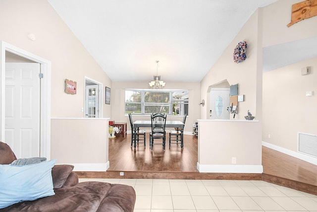 tiled dining room with high vaulted ceiling and a chandelier