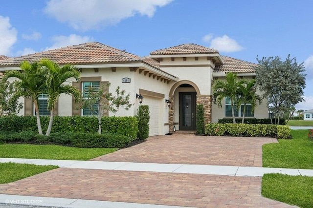 mediterranean / spanish house featuring a front yard and a garage