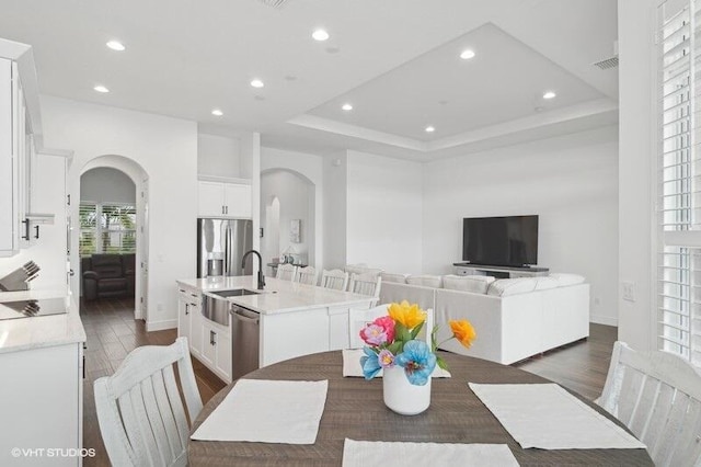 dining room featuring dark hardwood / wood-style floors, a tray ceiling, and sink