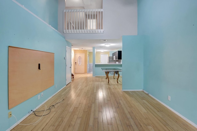 interior space featuring a towering ceiling and light hardwood / wood-style flooring