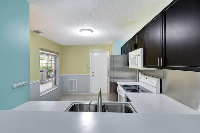 kitchen featuring a textured ceiling, sink, and white appliances