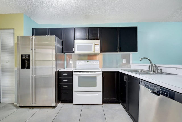 kitchen with a textured ceiling, appliances with stainless steel finishes, light tile patterned flooring, and sink