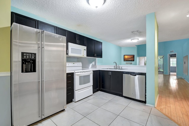 kitchen with light tile patterned floors, sink, stainless steel appliances, and a textured ceiling