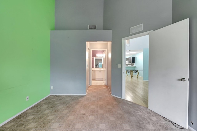 carpeted empty room featuring a high ceiling