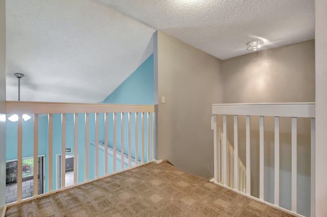 corridor featuring a textured ceiling, lofted ceiling, and carpet floors