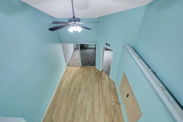 interior space featuring ceiling fan, light hardwood / wood-style flooring, and a towering ceiling