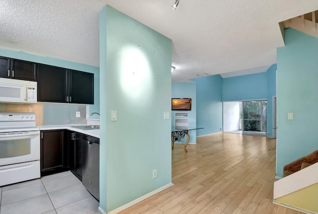 kitchen with a textured ceiling, sink, light wood-type flooring, and white appliances