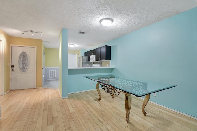 dining room with a textured ceiling and light wood-type flooring