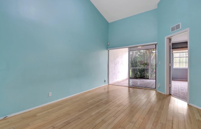 empty room with light hardwood / wood-style floors and high vaulted ceiling