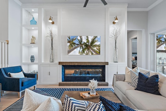 living room with built in shelves, ornamental molding, and wood-type flooring