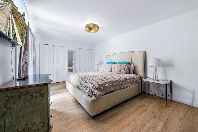 bedroom with two closets and light hardwood / wood-style floors