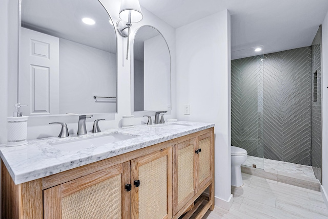 bathroom featuring toilet, vanity, and a tile shower