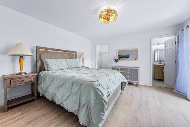 bedroom with a walk in closet, a closet, connected bathroom, and light hardwood / wood-style flooring