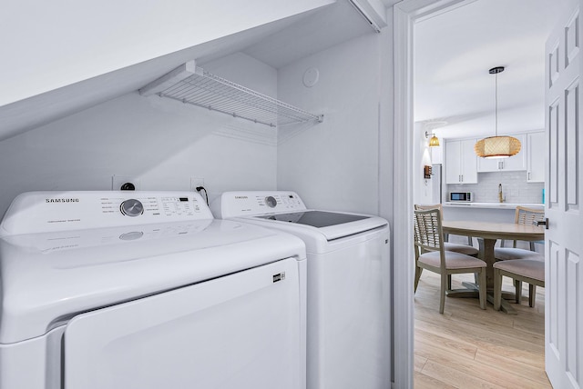 clothes washing area with sink, light hardwood / wood-style flooring, and washing machine and dryer