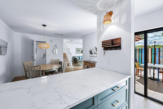 kitchen featuring light hardwood / wood-style floors, light stone counters, and pendant lighting